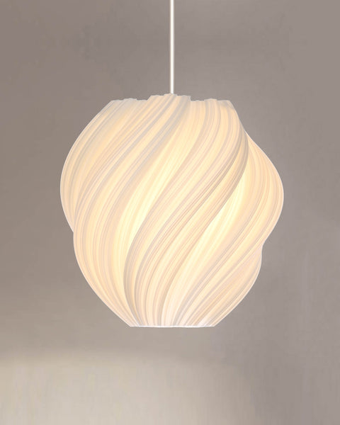 Morandi Cristallo #2 Anticlockwise pendant lit with a soft warm glow on a white cord against a warm grey studio wall